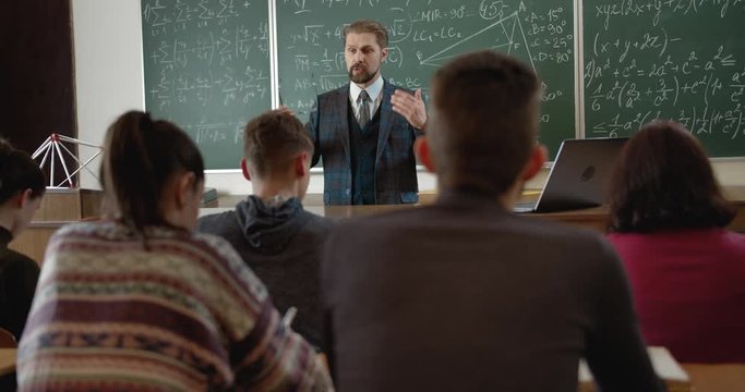 Handsome male lecturer giving lesson to students, explaining math
