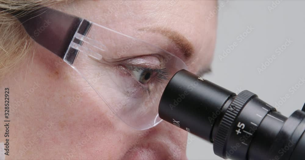 Wall mural close-up of woman scientist using microscope in a laboratory.