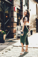 Smiling woman drink coffee walking on the city in summer day.