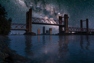 Spijkenisse bridge at night with milky way. River Maas waterfront view of open bridge part and the skyline of Spijkenisse on the background. Photomanipulation