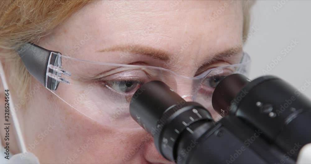 Wall mural close-up of woman scientist using microscope in a laboratory.