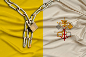 iron chain and lock on vatican silk national flag with beautiful folds, the concept of a ban on...