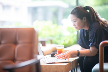 Attractive asian woman smiling, texting and messaging in computer tablet application for online payment or money transfer and looking at notification on smartphone feeling positive in cafe