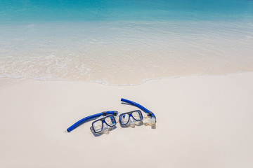 Diving goggles and snorkel gear on white sand near beach. Summer vacation and recreational travel background