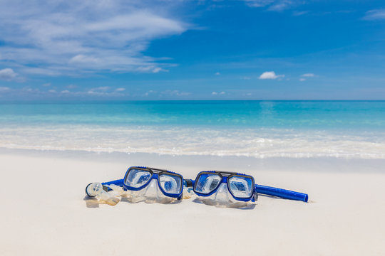 Diving goggles and snorkel gear on white sand near beach. Summer vacation and recreational travel background