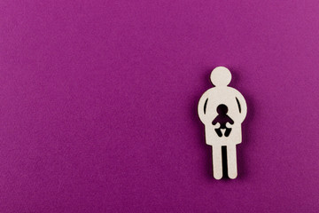 Mother and child. Pregnancy. Wooden figure on purple background.