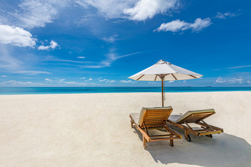 Luxury lifestyle concept with two sun chairs and umbrella over white sand under blue sky. Summer beach landscape, amazing tranquil view. Beach travel or vacation background