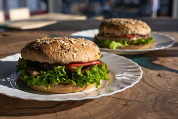 Big sandwich - hamburger with juicy chicken burger, cheese, tomato, and red onion on wooden background