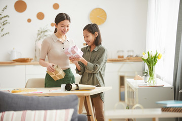 Horizontal shot of happy young Asian woman and teen girl preparing gift boxes for Mothers Day holiday, copy space