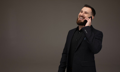 Close up portrait of young businessman with beard talking with mobile phone