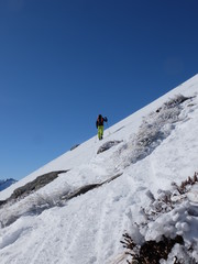 Alpiniste qui grimpe dans la neige et la glace de la montagne avec des b&acirc;tons et des crampons sous le ciel grand bleu