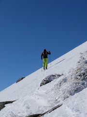 Fototapeta na wymiar Alpiniste qui grimpe dans la neige et la glace de la montagne avec des bâtons et des crampons sous le ciel grand bleu