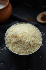 A scattering of rice, a handful of rice, rice in a metal bowl on a dark background. 