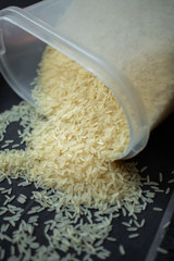 A scattering of rice, a handful of rice, rice in a metal bowl on a dark background. 