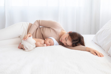 Obraz na płótnie Canvas Adorable newborn baby sleeping on bed in mother arm nursing, young Asian beautiful mother lying down hold hug infant 0-1 month with love, gently, happy sleeping trust safe caring lovely motherhood