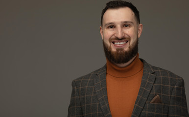 Portrait of a handsome bearded man smiling against grey background with copy space.