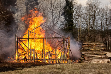 Fototapeta na wymiar Dangerous fire. Whole house and yard on fire. A fire destroys a charred burnt house