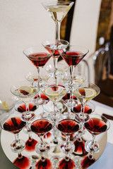 Pyramid of glasses with Martini cocktail for a festive reception at the wedding on the table. Cosmopolitan cherry cocktail Isolated.