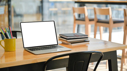Cropped shot of Laptop with notebooks and stationary on a wooden desk in a modern office.