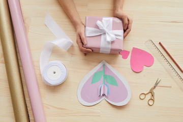 Horizontal from above flat lay composition of cards, decorations and hands holding gift box for Mother's Day