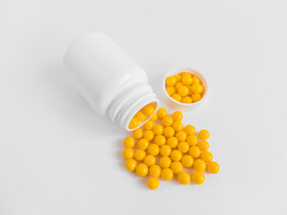Vitamins. Antiviral drug tablets. Round yellow healthy pills and pill bottle on white background....
