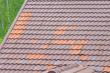 Metal tiles with burnt paint and rust on the roof of building.Soft focus.Concept of defects,damage polymeric coating of metal roofing tiles system in residential and commercial construction.