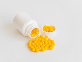 Vitamins. Antiviral drug tablets. Round yellow healthy pills and pill bottle on white background....