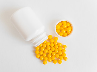 Vitamins. Antiviral drug tablets. Round yellow healthy pills and pill bottle on white background....