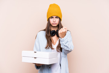 Young caucasian woman holding pizzas isolated showing fist to camera, aggressive facial expression.