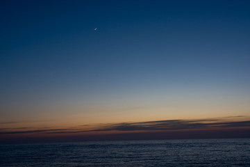静かな海の夕暮れと三日月
