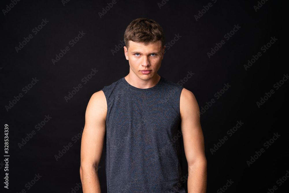 Wall mural Portrait of young man over isolated black background