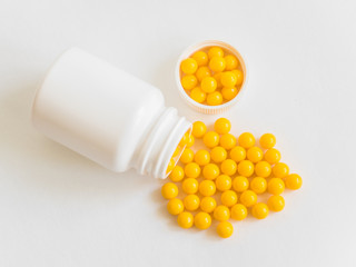 Vitamins. Antiviral drug tablets. Round yellow healthy pills and pill bottle on white background....