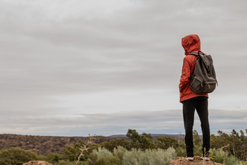 young backpacker looking at the horizon with cloudy, grey sky