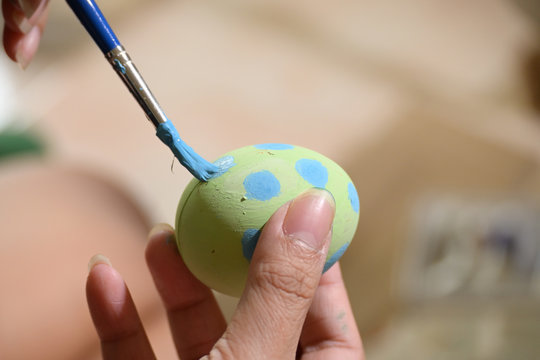 people using paintbrush green and blue watercolor painting on easter egg design custom pattern handicraft for celebration