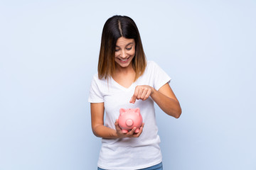 Fototapeta na wymiar Young woman over isolated blue background holding a big piggybank