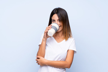 Young woman over isolated blue background holding and drinking a coffee to take away