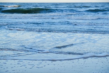 Sea shore with waves flooding the sand and creating interesting patterns. Baltic Sea, Dziwnowek, Poland