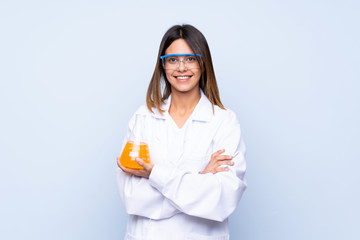 Young woman over isolated blue background with a scientific test tube