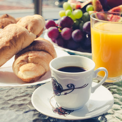 Breakfast table with coffee, orange juice, fruits and croissants
