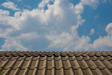 The house old roof with the cloudy blue sky background in the sunny day. 