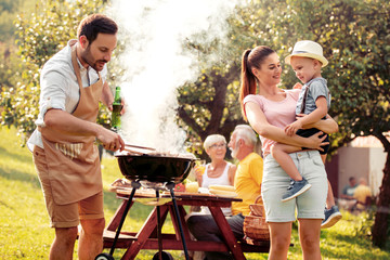 Family makes barbecue together. - obrazy, fototapety, plakaty