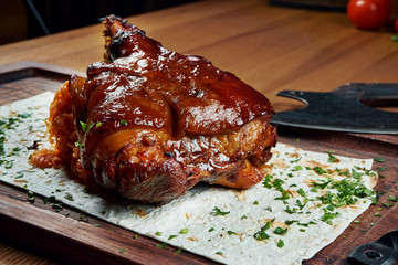 A classic dish of German and Czech cuisine is pork shank in beer and honey sauce on a wooden board. Beer snack. Tasty food close up. Roasted pork knuckle eisbein