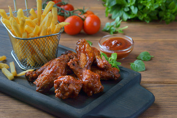 barbecue wings with French fries on a dark background