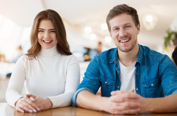 young couple beautiful woman and handsome man sitting at cafe during coffee break, both looking happy, body language concept