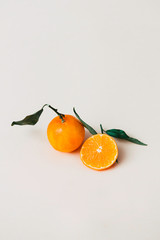 Stock photos of piece of tangerine or orange fruit split in half on a minimalist cream background