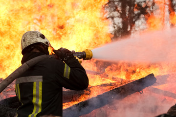 Brave firefighter saving burning building. Firefighter work concept. Firefighter are using water in...