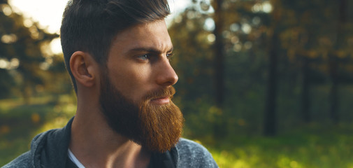Portrait of handsome bearded man with hoodie in forest Close up wide portrait profile Natural...