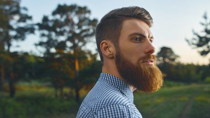 Portrait brutal bearded hipster man in the forest Long red beard Blue shirt Copy free space for advertising
