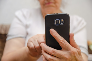 Black mobile phone in the hand of an elderly woman close up