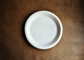 Empty plate paper ECO on brown clothing background, Photo top view and copy space